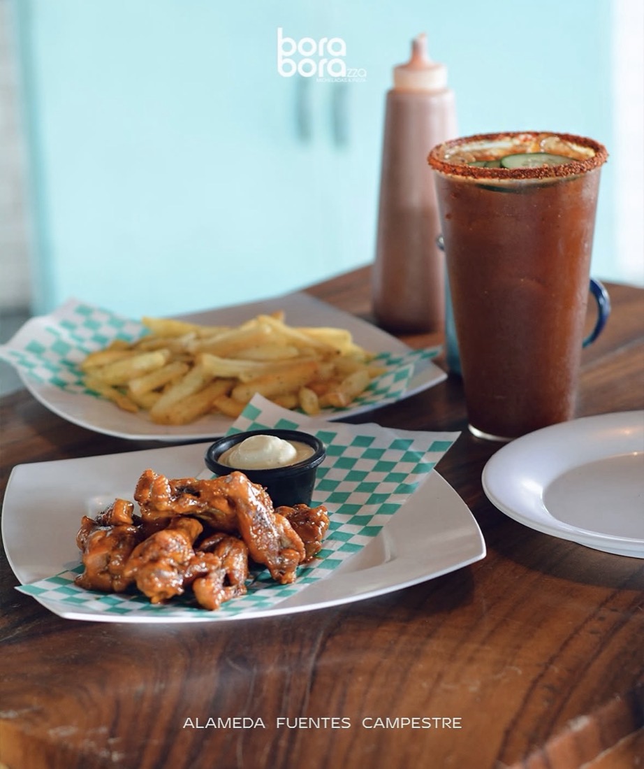 Alitas, papas y michelada sobre la mesa